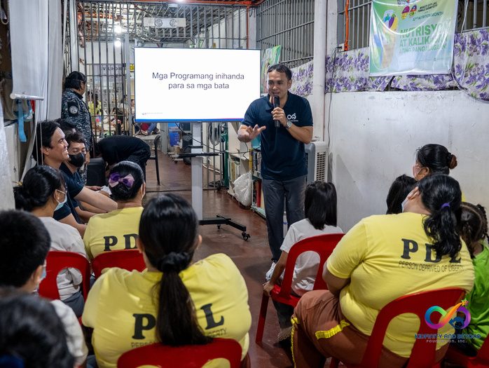 A Foundation board member presents a slide titled “Mga Programang inihanda para sa mga bata” to mothers in yellow PDL shirts.